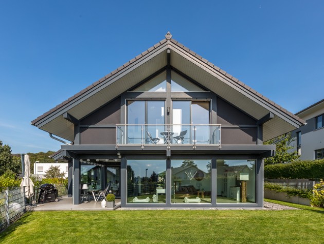 Modern post and beam black timber frame eco home with pitched roof panoramic glazing and glass balcony