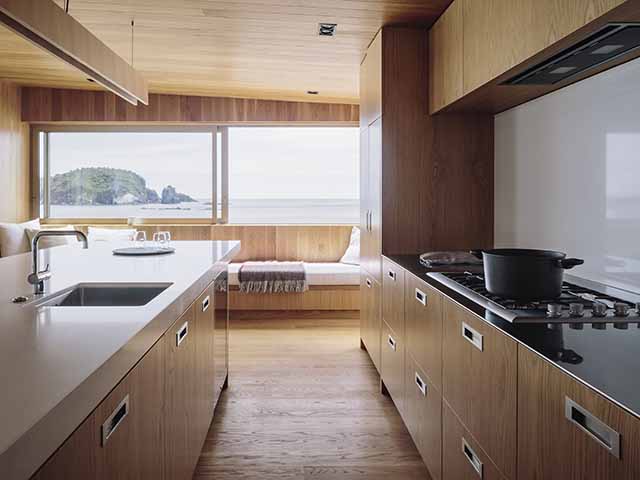Looking through a galley kitchen with timber cabinets and a white work surface.