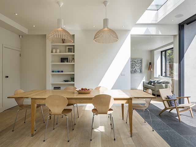 Dining table and chairs in an open area that's part of a broken plan kitchen layout
