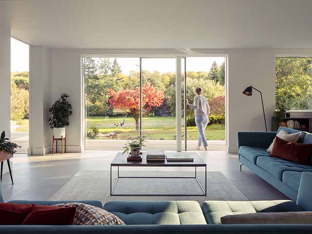 Victorian cottage living room with sliding doors out to the garden with woman pushing them open