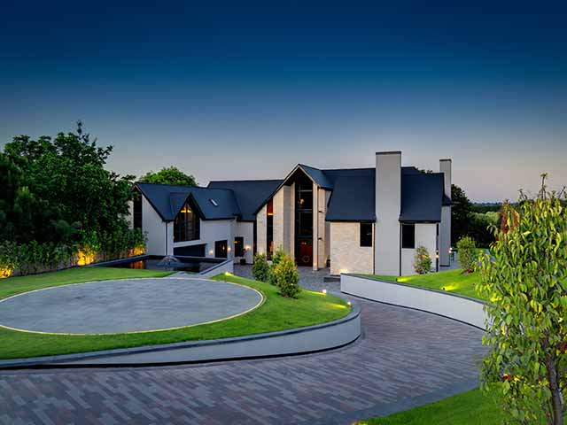 A large house with curving driveway and helipad in the centre