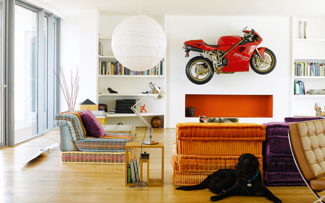 Colourful living room in the Grand Designs mansion with a red motorcycle mounted on the wall