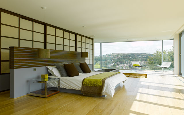 View of a spacious bedroom with floor-to-ceiling windows that provide views from the top of the house