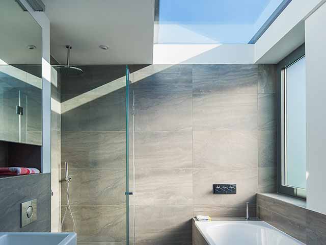 Loft bathroom with overhead glazing and grey porcelain wall tiles