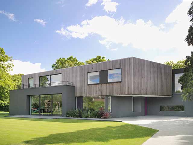 A contemporary house exterior with grey rendered ground floor walls and timber cladding above
