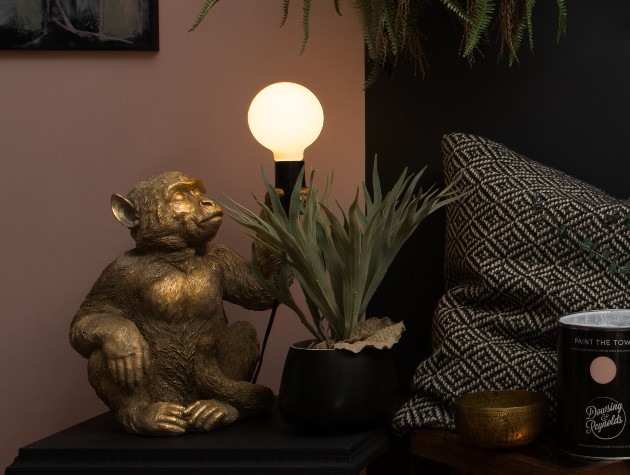 Contemporary interior featuring dark walls sitting monkey lamp geometric monochrome cushion and faux foliage