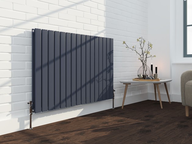 black modern radiator in room with white tiled wall table and plant