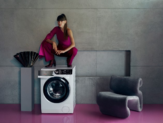 woman squatting on washing machine next to modern chair