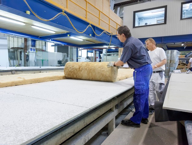 two men rolling out insulation in factory