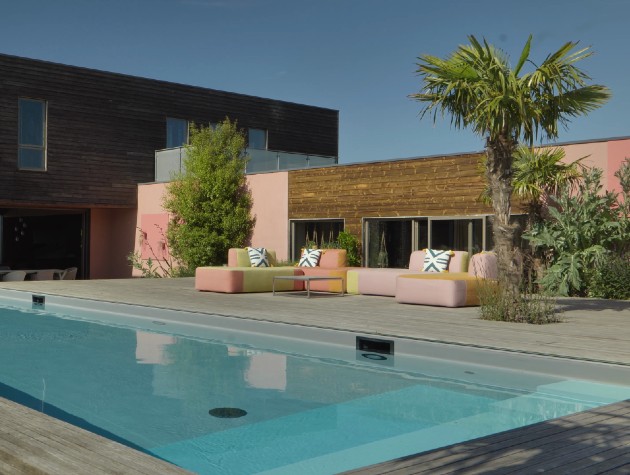 Blue swimming pool and patio area with modern furniture outside new build home