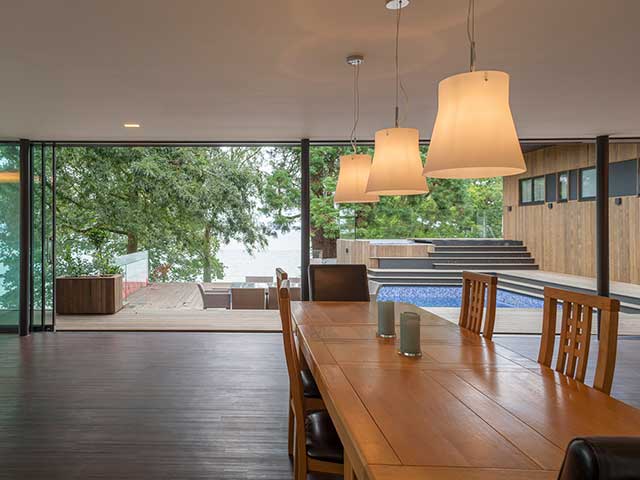 Dining room has sliding clear doors that open to elevated wooden decking space and swimming pool