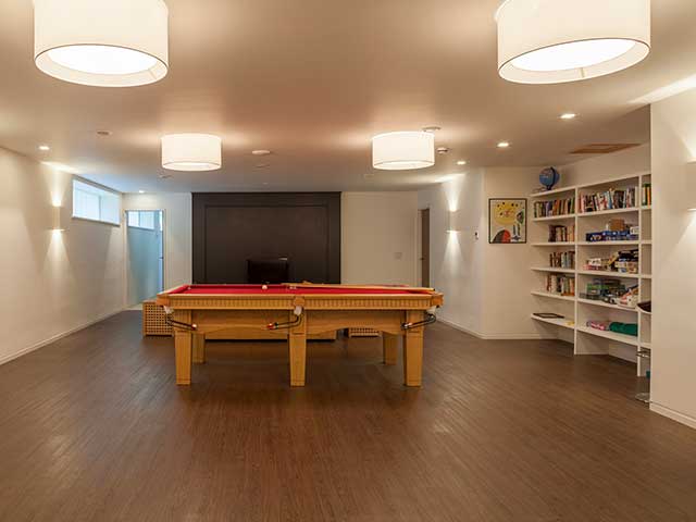 Red pool table in games room with tv and bookshelves on wooden floor of Grand Designs Isle of Wight home