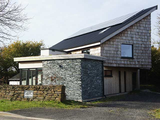 Solar panels on stone home with gravel driveway