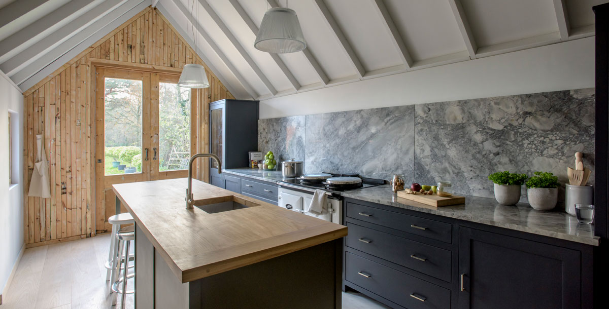 barn conversion kitchen in west sussex with timber beam ceiling and dark kitchen fittings