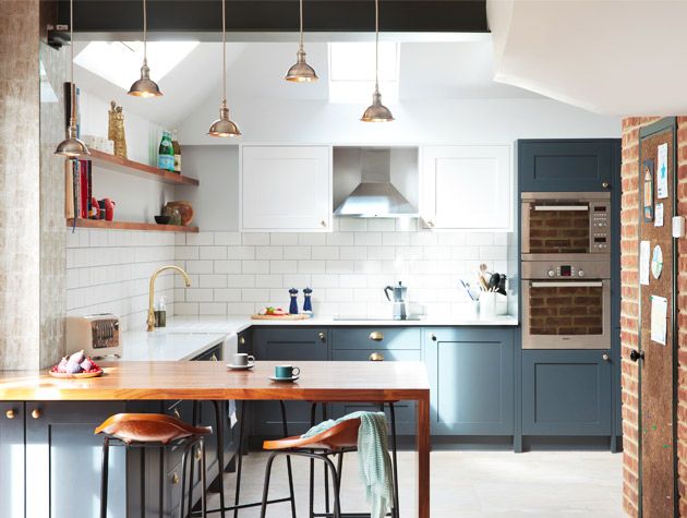 kitchen with exposed brick wall, peninsula breakfast bar and high ceiling with skylights