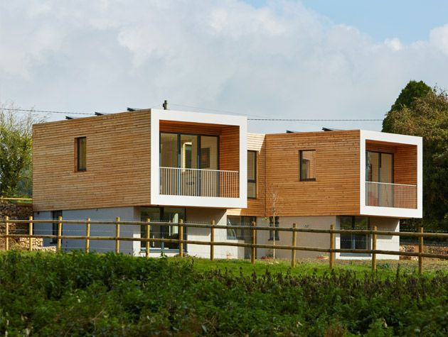 The exterior of a house with symmetrical cantilever first floor wings. The top floor is clad in cedar boards.