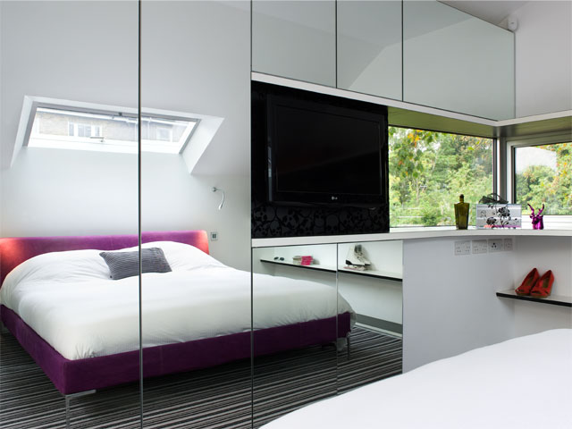 Minimalist bedroom with mirrored wardrobes and built in tv