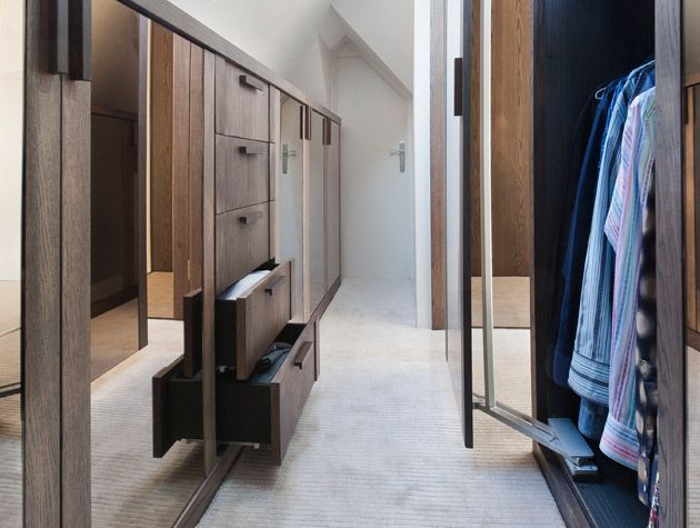 simplify your space. walk in wardrobe with full height dark drawers folding wardrobe doors men's multicoloured shirts white walls and ceiling
