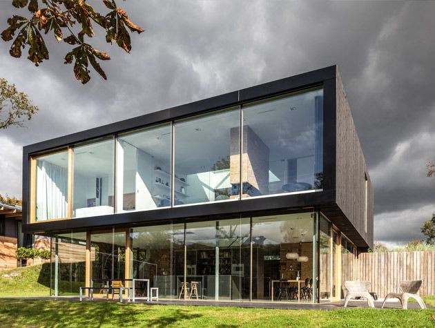 Contemporary three storey home under grey sky wooden fence 