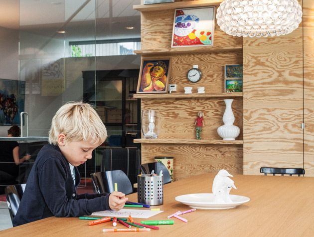 Child drawing in front of wooden shelves 