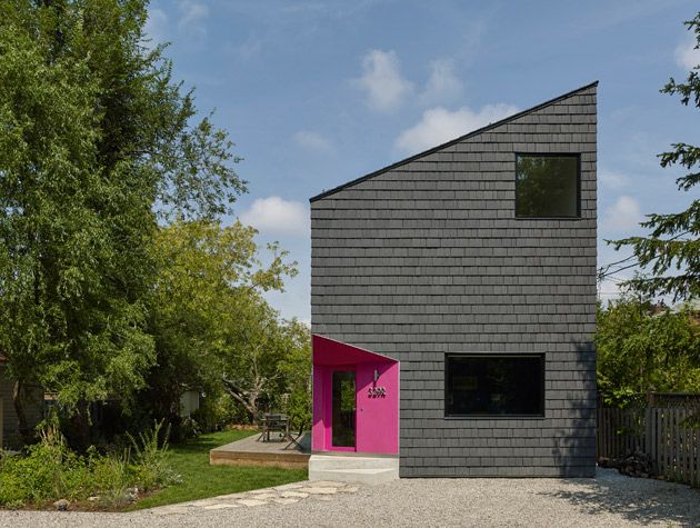 Black clad modern home exterior with pink recessed door 