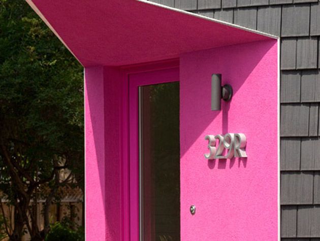 Recessed pink front door on black clad home close up