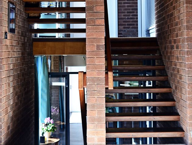 peter womersley exposed brick staircase wooden stairs white plant pot with purple flower