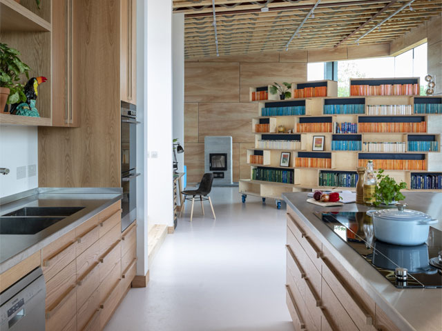 A curved bookshelf on wheels, designed and built on site out of ply boxes by local artist Ravi Baines, acts as a moveable room divider and provides sound absorption in the open-plan space