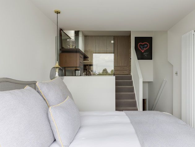 L-shaped loft conversion bedroom with split levels for bed and dressing room area separated by stairs -rees-architects-conversions-granddesignsmagazine.com