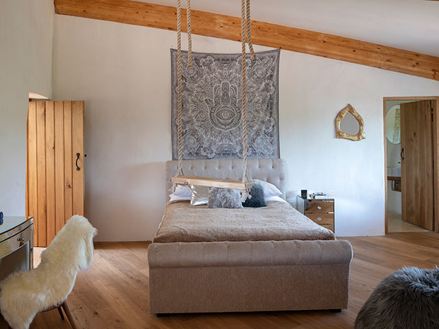 Children's bedroom with wooden beams, wooden flooring and rope swing. Grand Designs Cob House