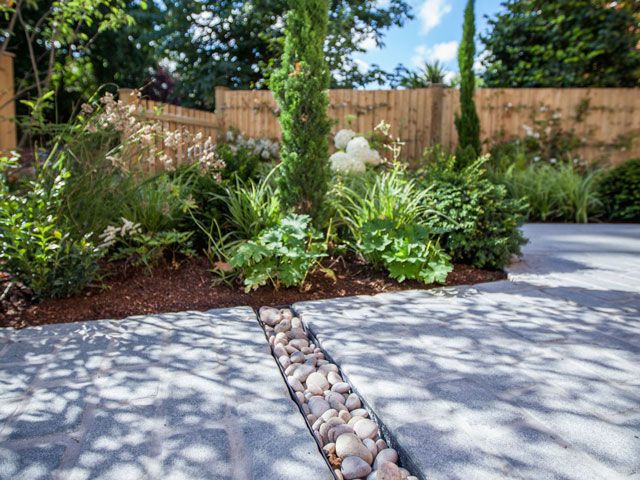 driveway with rocks and a garden by Simon Orchard Garden Design