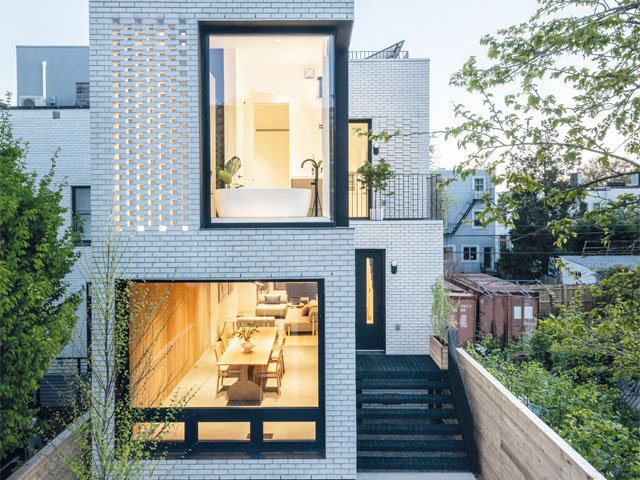 White brick home with large glazed black windows and balcony with industrial railings