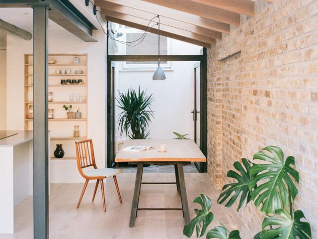 Brick walled interior dining area with inbuilt bookcase and doors leading to small courtyard