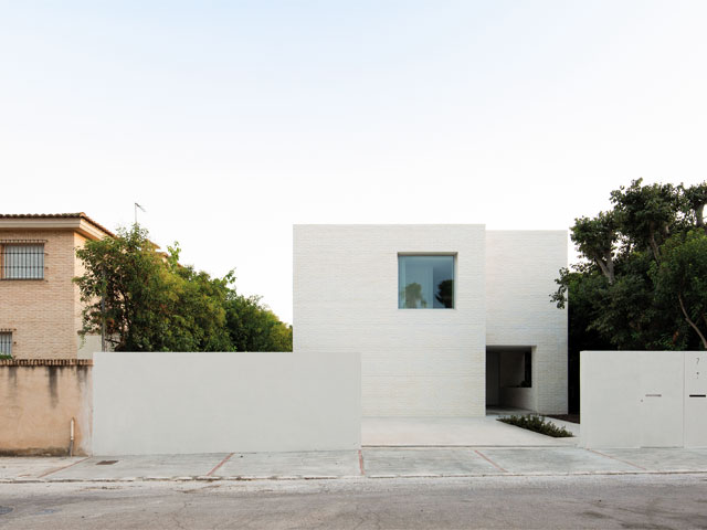 White brick home with single square window and white wall