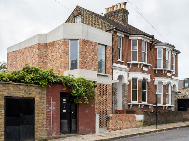 Lattice brick semi detached home extension with portrait windows next to painted garages