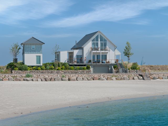 A modular Baufritz self-build by the sea with grey pitched roof and, huge windows and white-rendered walls in Flensberg, Germany