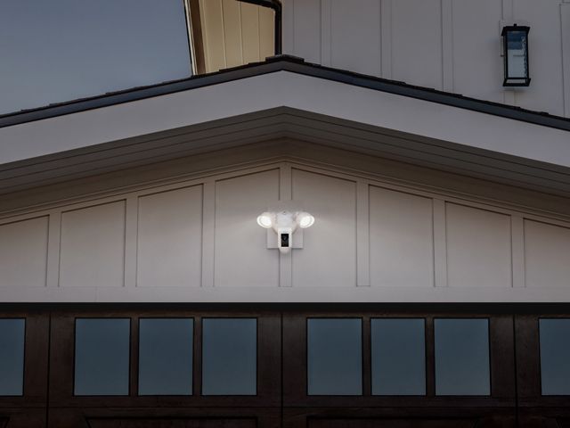 a ring floodlight cam affixed to a garage by a house