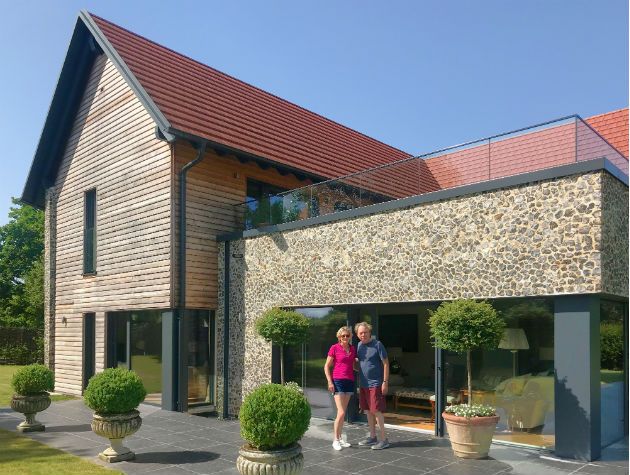 Outside Andrew Lloyd Webber's Baufritz house in the country with green plants and blue skies