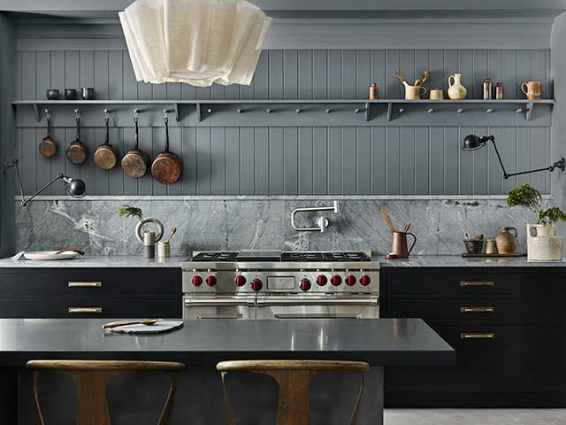 Granite kitchen worktop with metal range cooker and panelled wall behind