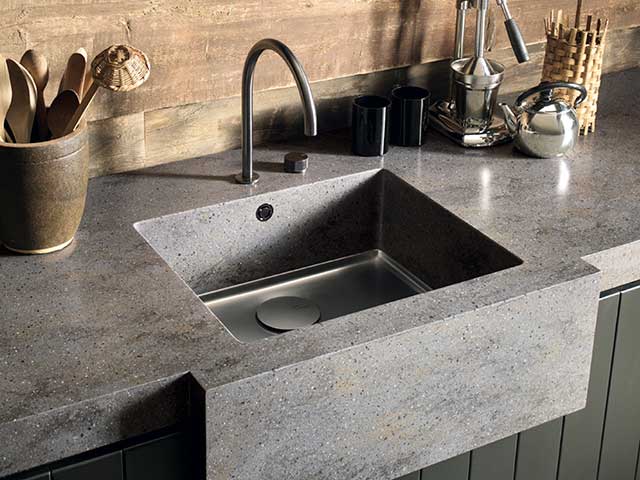 Stone and concrete kitchen worksurface with utensils and sink built-in