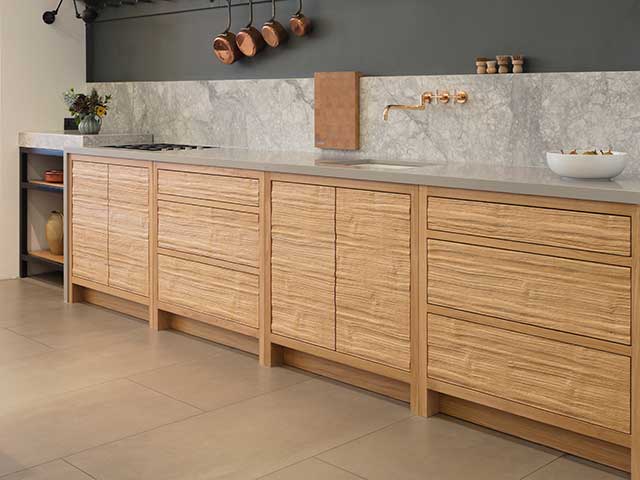 Grey quartz kitchen worktop contrasted with wooden units and marbled background