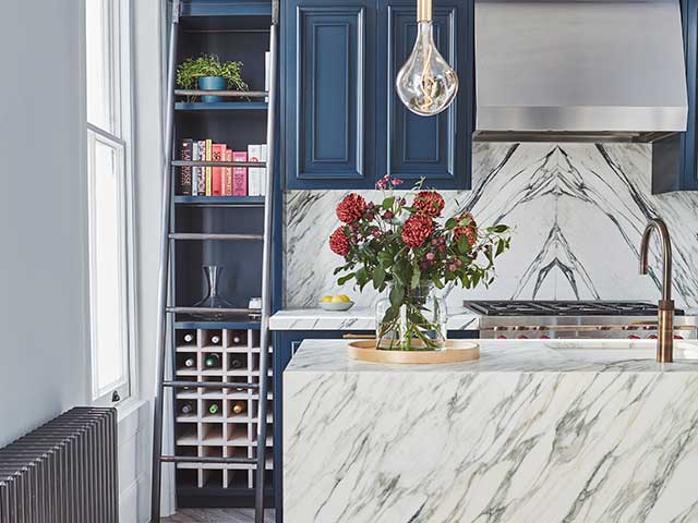 Slip matched marble worktop with navy units and brass sinks