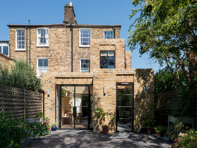 brick home exterior with wraparound extension potted plants large tree