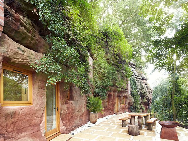 exterior of the cave house from grand designs with living wall and rustic wooden picnic bench on the patio