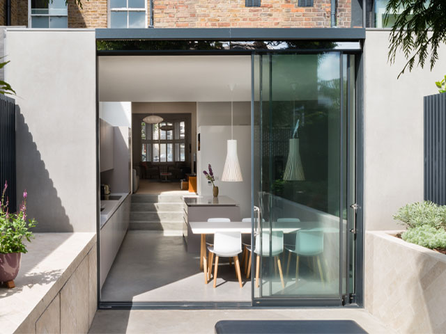 rear extension with floor-to-ceiling glazed doors and matching flooring that flows onto the terrace
