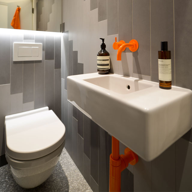 colourful taps in a quirky small washroom with grey tiles