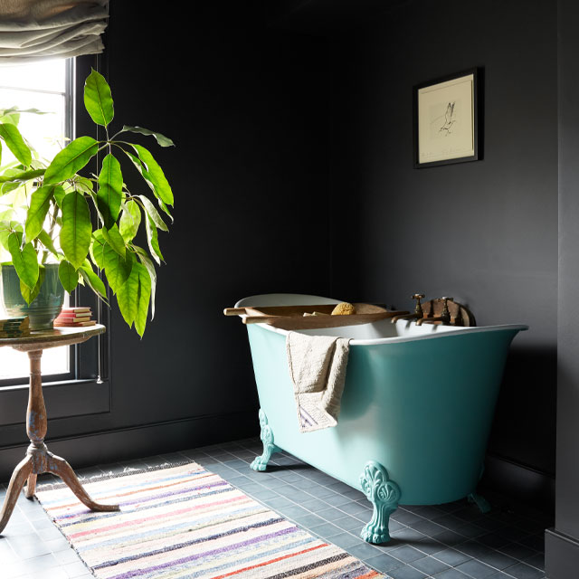 Vintage bathroom ideas: salvaged roll top bathtub with dark walls and green plants