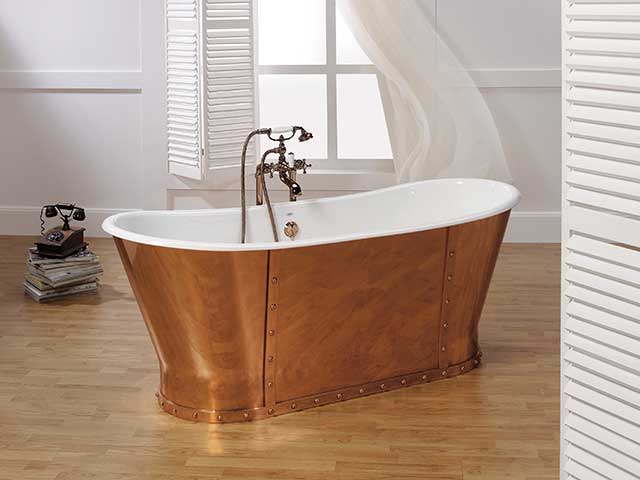 Copper bath with white interior on wooden flooring with white panels beside