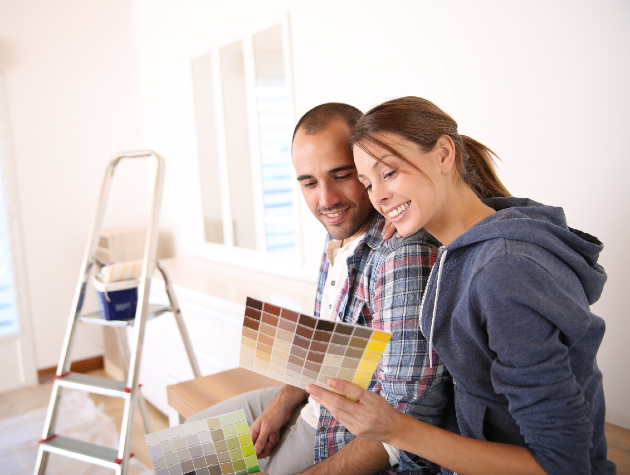 couple looking at paint colour charts as they decorate a newly insulated home