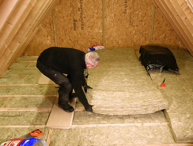 man laying stone wool insulation in loft space